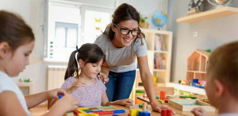 Preschool teacher with children playing with didactic toys